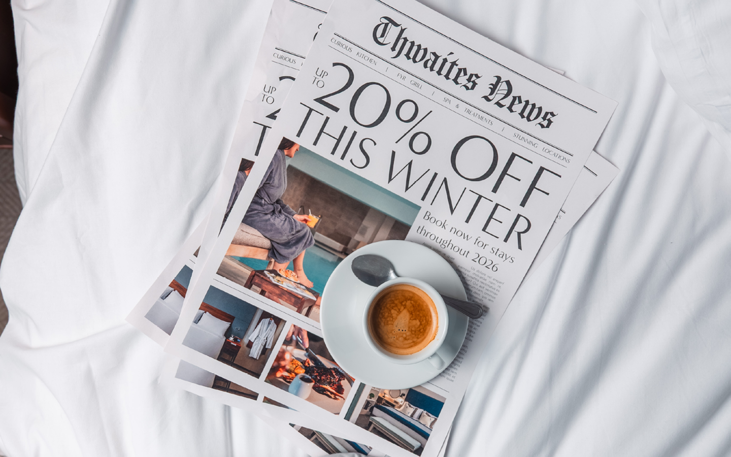 Newspaper and coffee on hotel bed with the headline "Up to 20% off this winter"