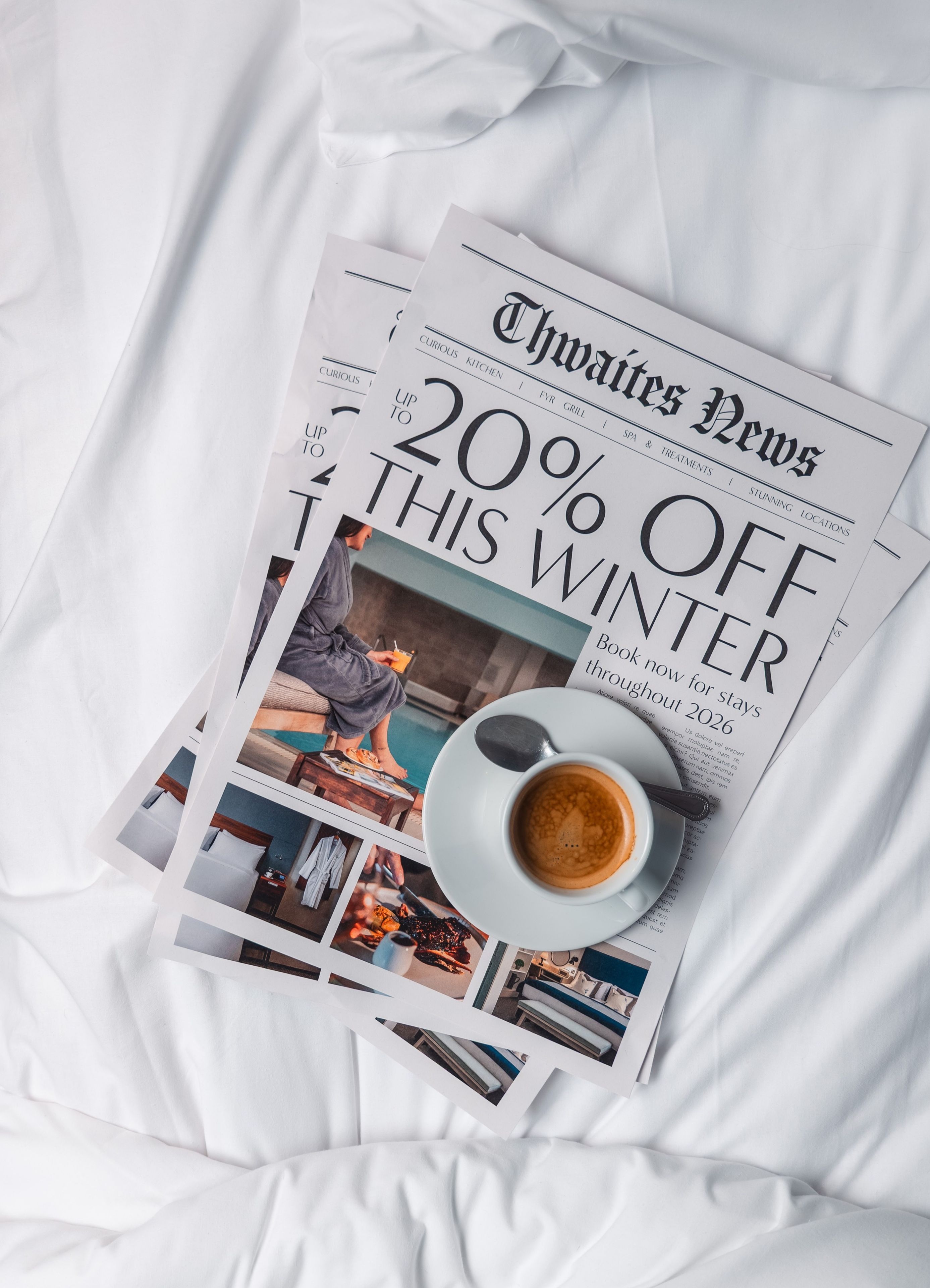 Newspaper and coffee on hotel bed with the headline "Up to 20% off this winter"