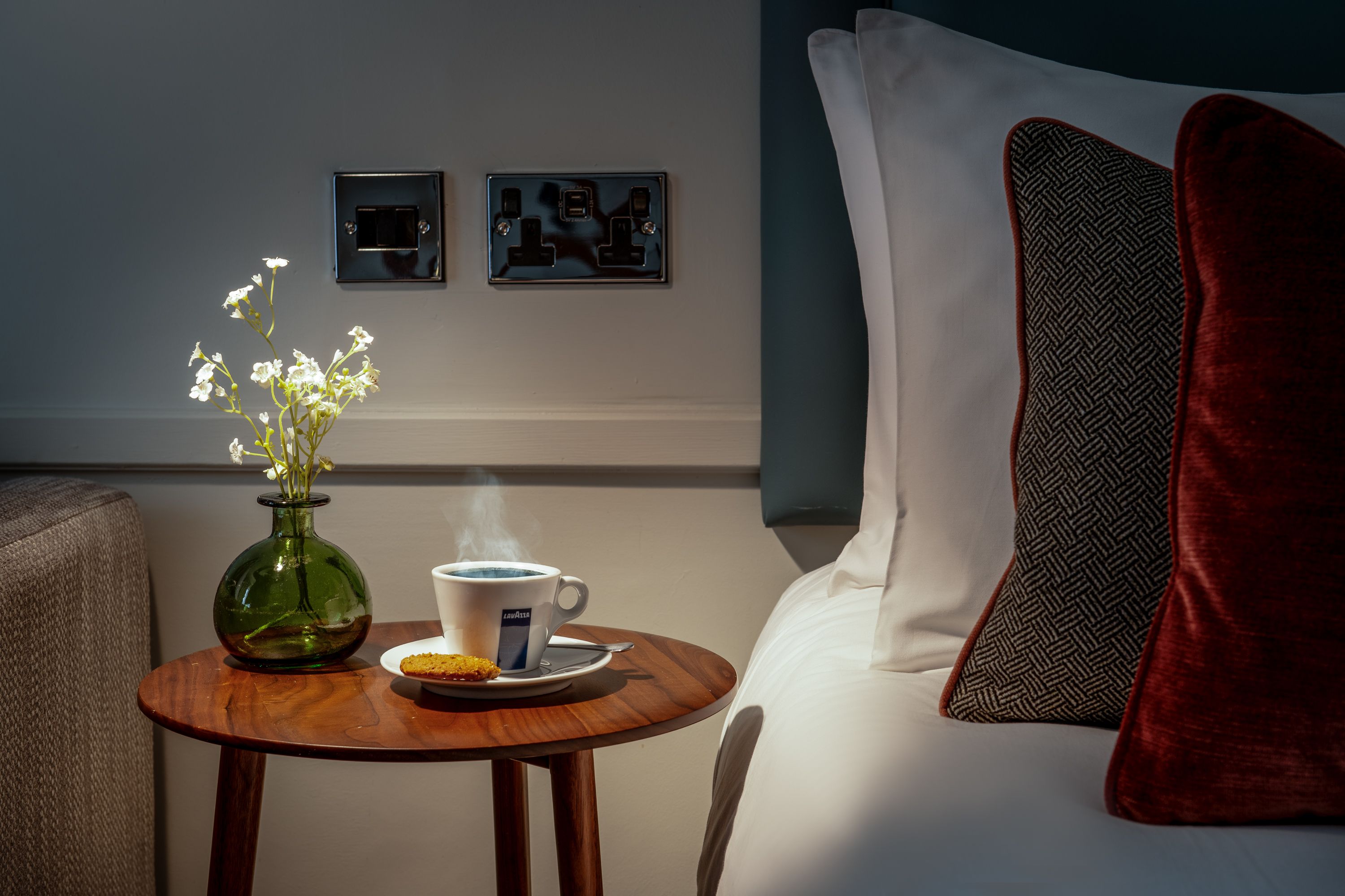 Close up of bedroom bed side table, with flowers and a cup of tea