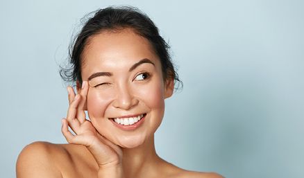 Woman winking whilst applying skincare