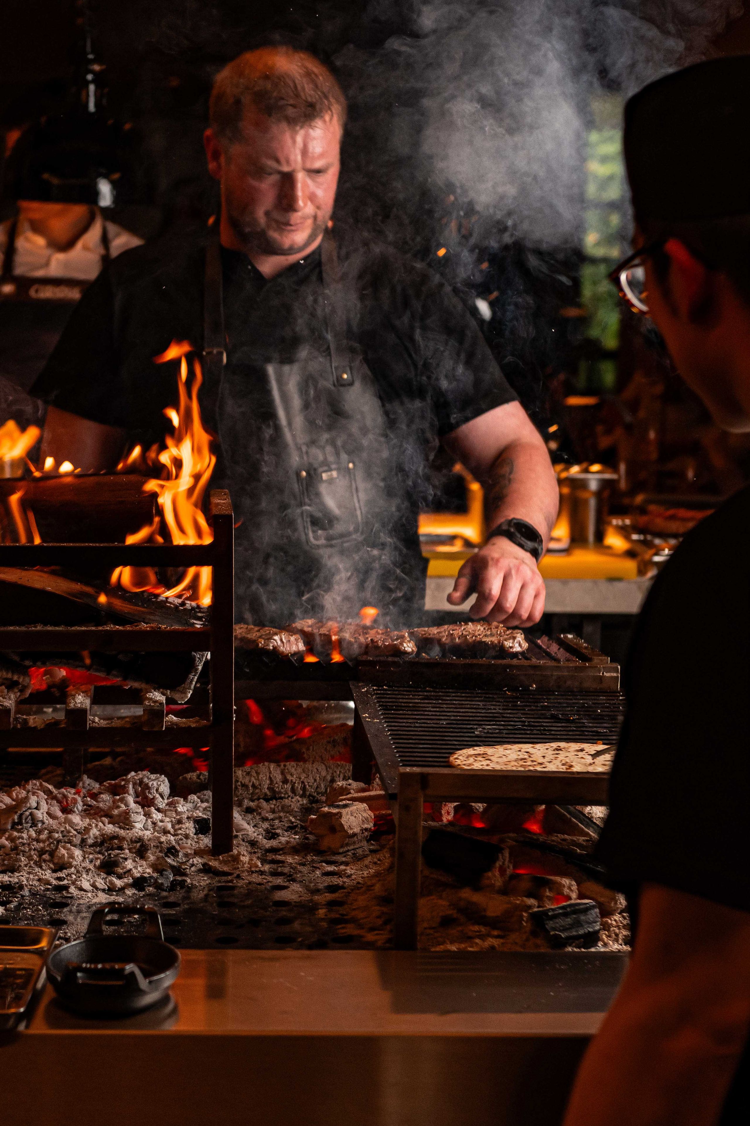 Chef cooking steak on a open FYR grill